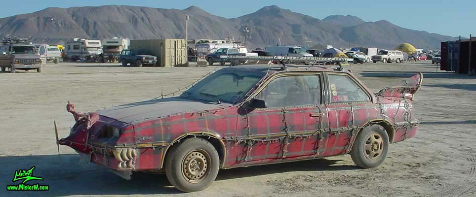 Photo of the Plaidmobile - Art Car / Mutant Vehicle, a 1985 Buick Skyhawk with a custom red plaid paint job, by Tim McNally in Black Rock City, Nevada, 2002. Tim McNally's Plaidmobile - Side View