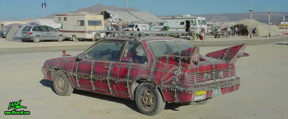 Photo of the Plaidmobile - Art Car / Mutant Vehicle, a 1985 Buick Skyhawk with a custom red plaid paint job, by Tim McNally in Black Rock City, Nevada, 2002. Tim McNally's Plaidmobile - Rear View