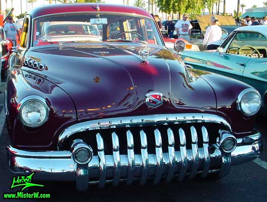 Photo of a maroon Buick Roadmaster Estate wagon, a Woodie station wagon with wood panels at the Scottsdale Pavilions Classic Car Show in Arizona. Front view of a 1950 Buick Roadmaster Estate wagon