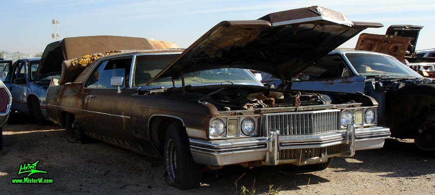 Photo of a brown 1973 Cadillac 2 door hardtop Coupe DeVille at a junk yard in Phoenix, Arizona. Front of a 1973 Cadillac Coupe DeVille