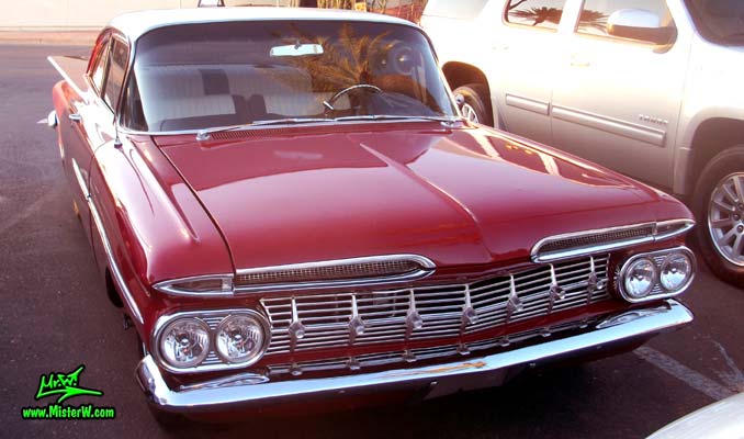 Photo of a red 1959 Chevrolet 2 Door Hardtop Coupe at the Scottsdale Pavilions Classic Car Show in Arizona. Front view of a 59 Chevrolet 2 Door Hardtop Coupe