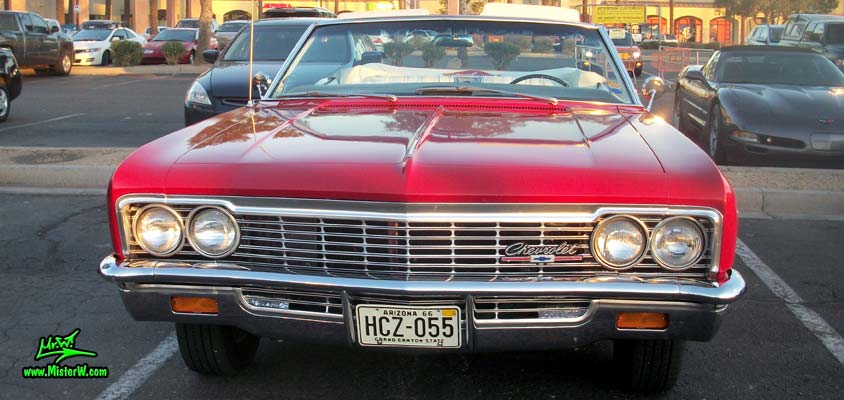 Photo of a red 1966 Chevrolet Impala Super Sport convertible at the Scottsdale Pavilions Classic Car Show in Arizona. Front view of a 1966 Chevrolet Impala Super Sport convertible