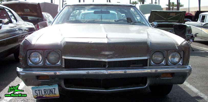Photo of a beat up brown & rusty 1972 Chevrolet 2 door hardtop coupe at the Scottsdale Pavilions Classic Car Show in Arizona. Front view of a 1972 Chevrolet Coupe