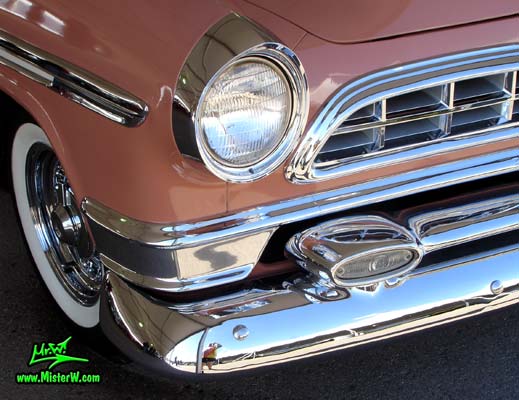 Photo of a pink & white 1955 Chrysler New Yorker Deluxe Town & Country Station Wagon at a classic car auction in Scottsdale, Arizona. Headlight of a 1955 Chrysler New Yorker Deluxe Town & Country Station Wagon