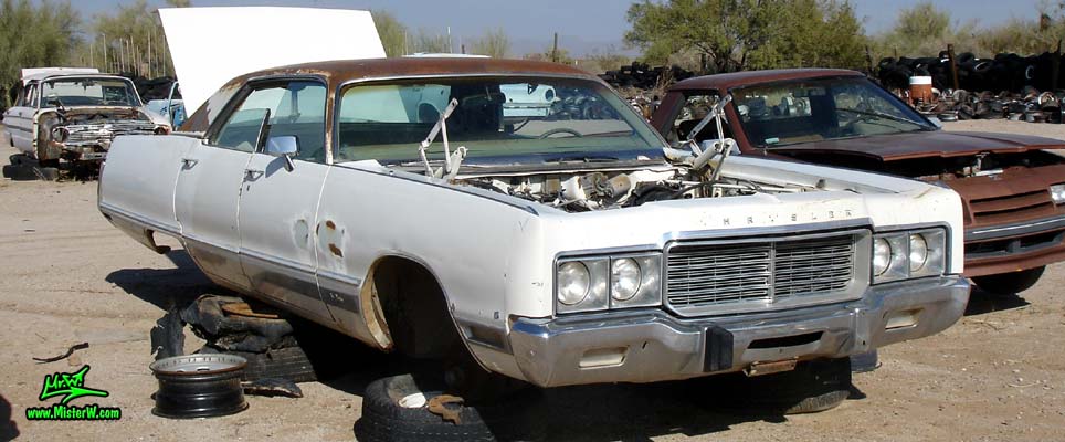 Photo of a white 1973 Chrysler New Yorker 4 door hardtop sedan at a junk yard in Phoenix, Arizona. Side view of a 1973 Chrysler New Yorker hardtop sedan