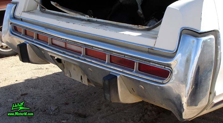 Photo of a white 1973 Chrysler New Yorker 4 door hardtop sedan at a junk yard in Phoenix, Arizona. Rear bumper & tail lights of a 1973 Chrysler New Yorker hardtop sedan