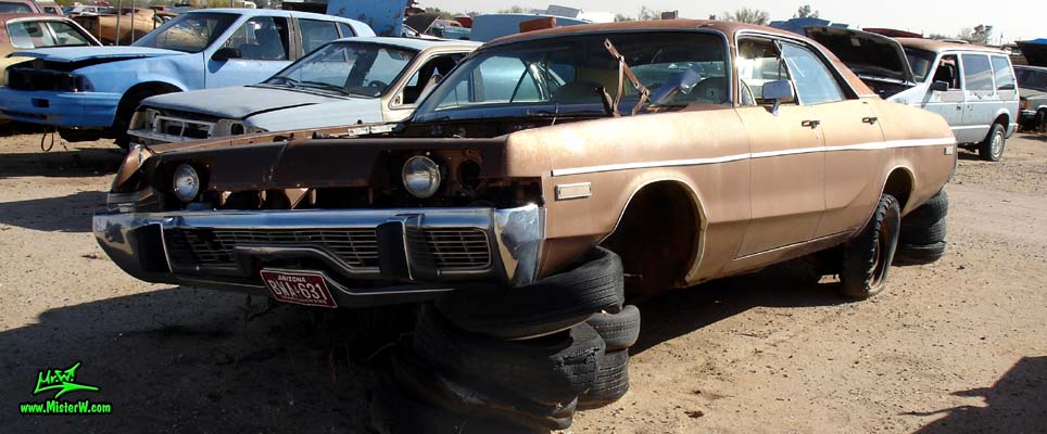 Photo of a brown 1973 Dodge Monaco 4 door hardtop sedan at a junk yard in Phoenix, Arizona. Frontview of a 1973 Dodge Monaco Hardtop Sedan