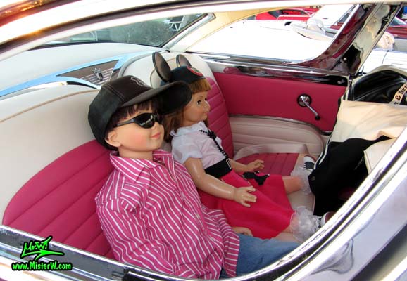 Photo of a pink & white 1955 Ford Crown Victoria 2 Door Hardtop Coupe at the Scottsdale Pavilions Classic Car Show in Arizona. Life Size Kids Dolls in a 55 Ford Coupe