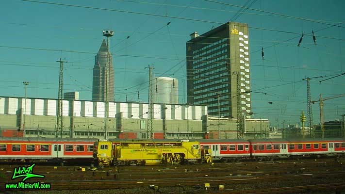 Photo of trains in front of the MesseTurm in downtown Frankfurt, taken from a ICE train Yellow Work Train in Frankfurt am Main