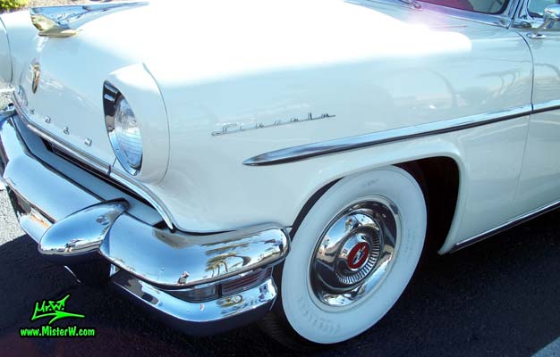 Photo of a white 1955 Lincoln Capri 2 door hardtop coupe at the Scottsdale Pavilions Classic Car Show in Arizona. Front chrome bumper & blinker of a 1955 Lincoln Capri hardtop coupe