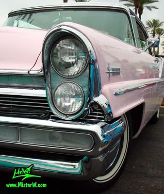 Photo of a pink & white 1957 Lincoln Premiere 2 door hardtop coupe at the Scottsdale Pavilions Classic Car Show in Arizona. Headlight & chrome trim of a 1957 Lincoln Premiere hardtop coupe