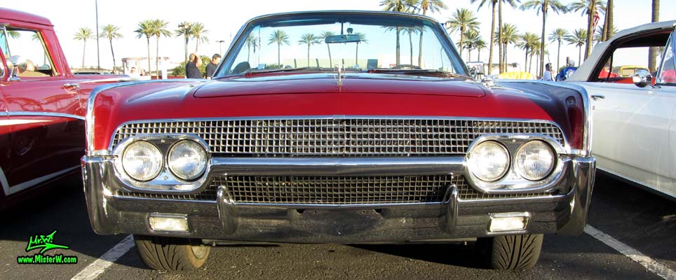 Photo of a red & white 1961 Lincoln Continental 4 door convertible at the Scottsdale Pavilions Classic Car Show in Arizona. Front view of a 1961 Lincoln Continental convertible