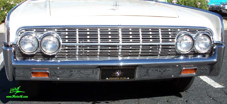 Photo of a white 1962 Lincoln Continental 4 door convertible at the Scottsdale Pavilions Classic Car Show in Arizona. Front chrome grill & bumper of a 1962 Lincoln Continental convertible