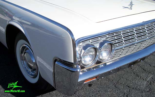 Photo of a white 1962 Lincoln Continental 4 door convertible at the Scottsdale Pavilions Classic Car Show in Arizona. Headlights & blimker of a 1962 Lincoln Continental convertible