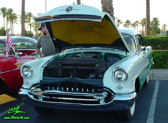 Photo of a white & turkquoise 1955 Oldsmobile 4 Door Hardtop Sedan at the Scottsdale Pavilions Classic Car Show in Arizona. 1955 Oldsmobile with open hood