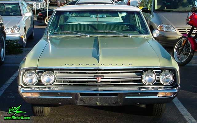 Photo of a olive 1964 Oldsmobile 2 Door Hardtop Coupe at the Scottsdale Pavilions Classic Car Show in Arizona. 1964 Oldsmobile Head Lights & Chrome Grill