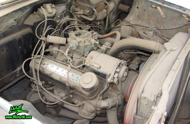 Photo of a grey primered 1956 Pontiac ambulance in Phoenix, Arizona. Dirty motor of a 56 Pontiac Ambulance Wagon
