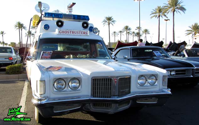 Photo of a red & white Pontiac Bonneville Ambulance at the Scottsdale Pavilions Classic Car Show in Arizona. Front Bumper of a 72 Pontiac Pontiac Bonneville Ambulance